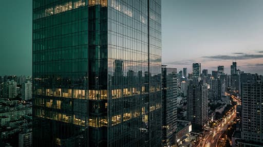 Modern glass skyscraper reflecting a twilight city skyline
